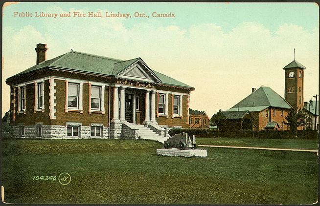 A red brick one storey library building next to a fire hall with tall clock tower and text Public Library and Fire Hall, Lindsay Ontario. 
