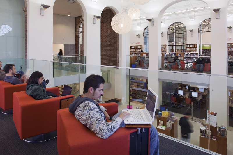 Patrons working on laptops in a library branch Patrons working on laptops in a library branch