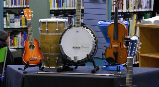 Musical instruments on display. From left to right: ukulele, hand drum, banjo, violin