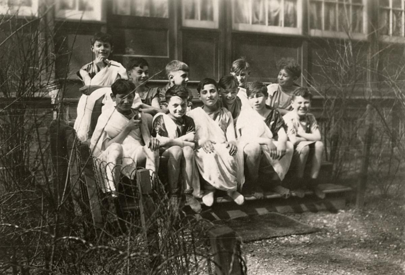 Picture of a group of boys dressed up for a play and sitting on the steps of Boys and Girls House
