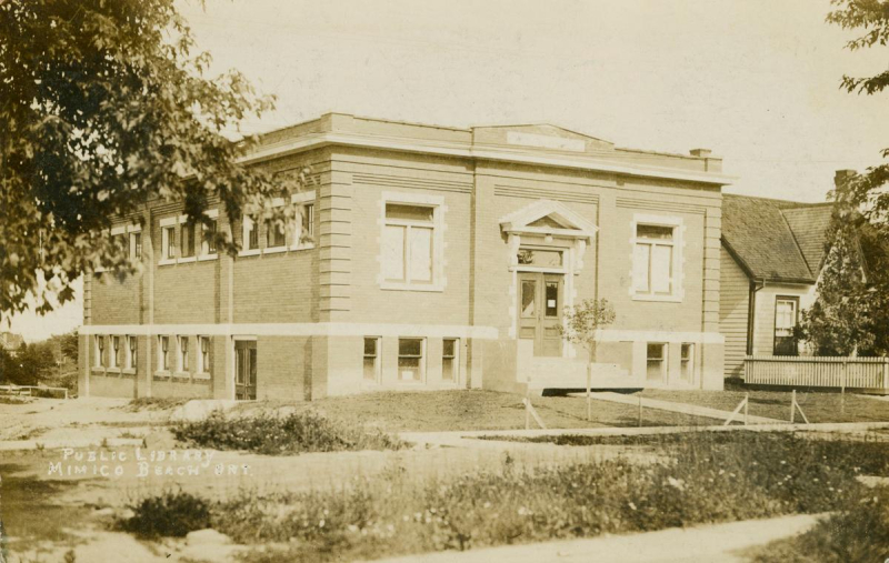 Sepia postcard of single storey square building in grassy residential area