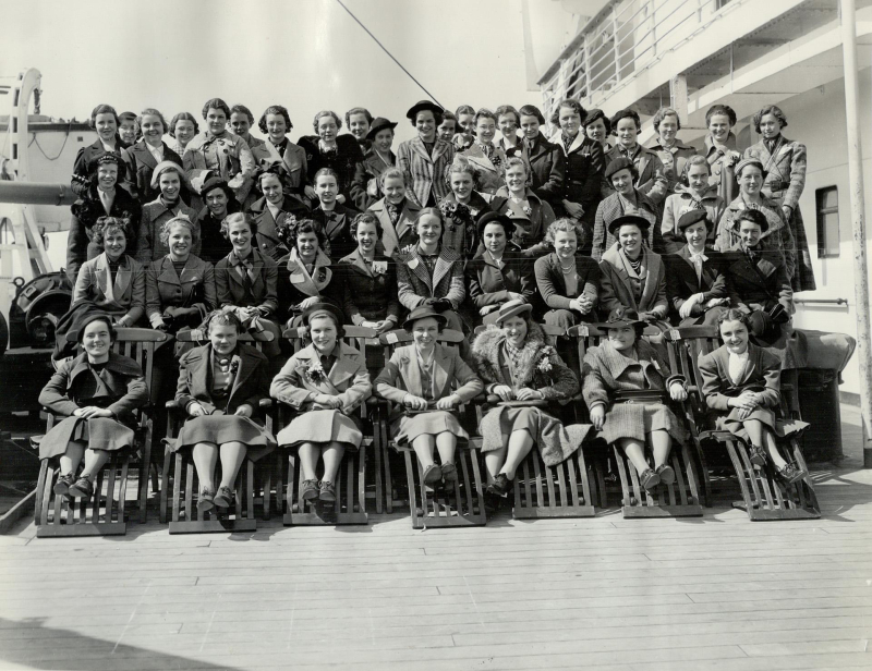 Vintage black and white photo of large group photo on deck of large boat showing high school aged girls smiling