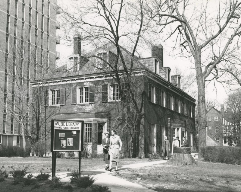 Old photo of two story building with sign reading Music Library Toronto Public Libraries and people walking nearby