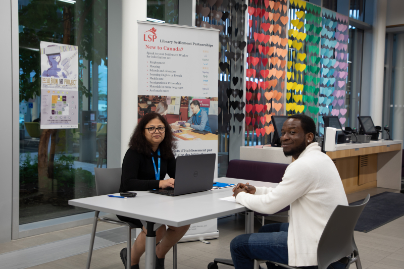 Settlement worker and customer smiling at the camera Settlement worker and customer smiling at the camera