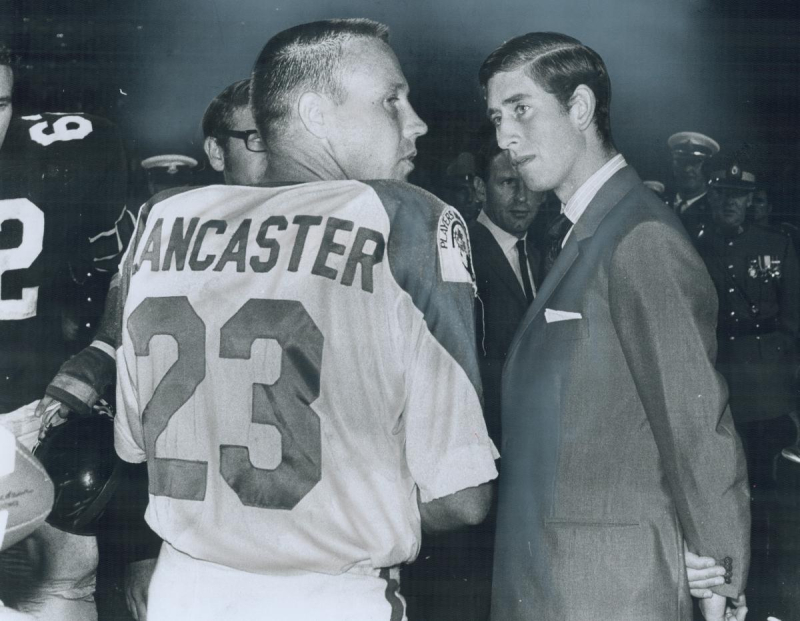 Prince Charles standing next to football player in jersey 
