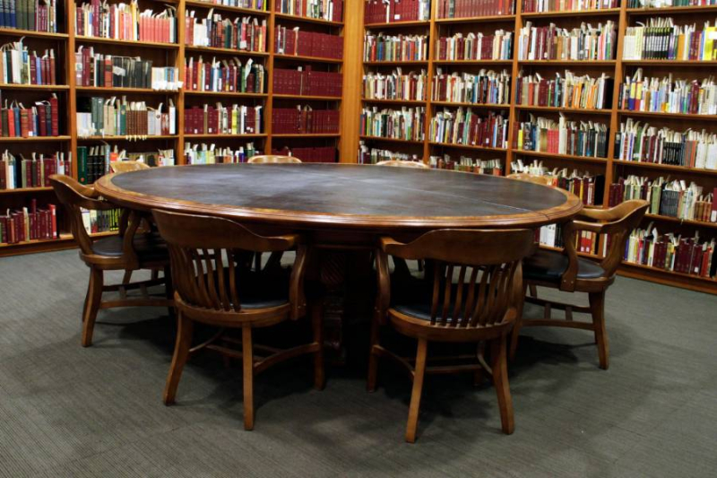 Large circular wooden table in modern library setting