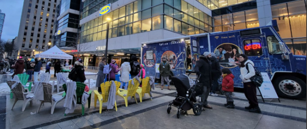 TPL's bookmobile parked at College Park, with customers waiting and receiving information outside. TPL's bookmobile parked at College Park, with customers waiting and receiving information outside.