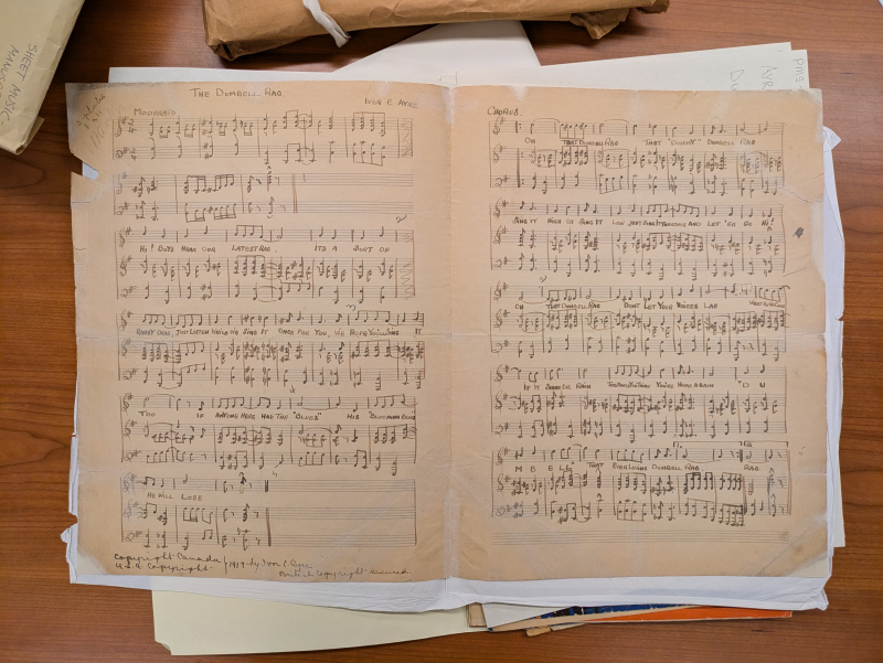 Open pages of worn sheet music titled The Dumbell Rag