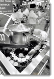 Ex-pert donut maker, Tom Brazier, owner-operator of Tiny Tom Donuts at the Canadian National Exhibition, makes sure each donut flips properly. 1991