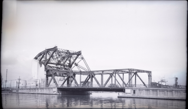 Black and white photo of steel lift bridge looking east along ship channel