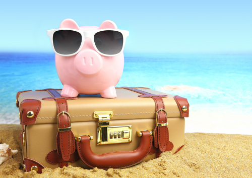 ceramic pink pig on a suitcase at the beach