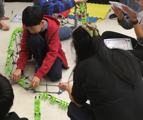People working together to put together the K'Nex Roller Coaster.