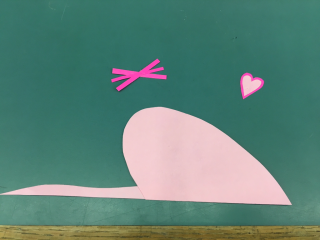 Three small dark pink strips glued together to make "whiskers". Two small hearts glued one on top of the other to make an "ear". Large heart folded in half with long strip of paper glued to the back as a "tail".