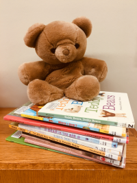 A teddy bear sitting on a pile of books.