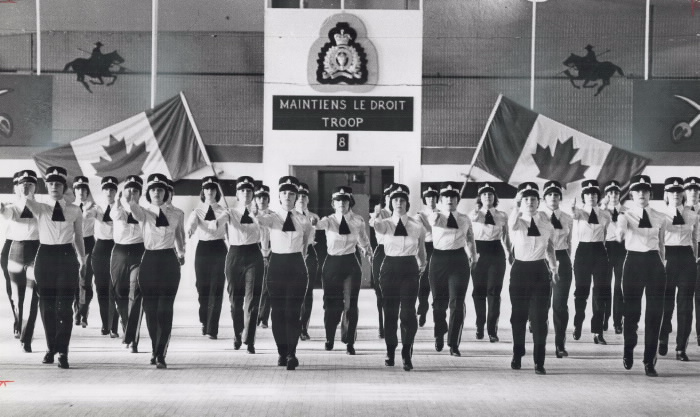 Lines of female recruits of Royal Canadian Mounted Police marching with Canadian flags