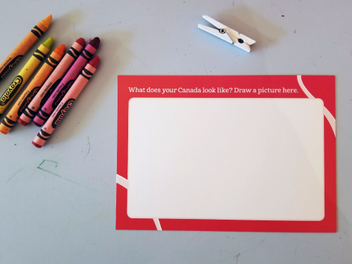 Crayons  blank postcard and clothes pin  all on table