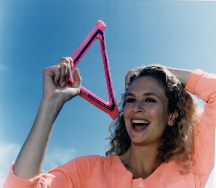 Smiling woman holds a pink trinangular boomerang toy