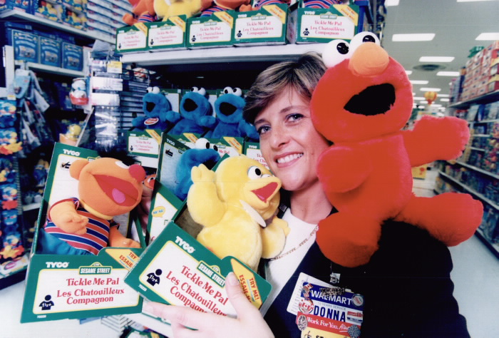 Inside a toy store a woman carries three stuffed animal toys