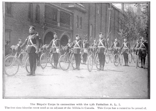 Men in military uniforms with rifles assemble standing beside bicycles