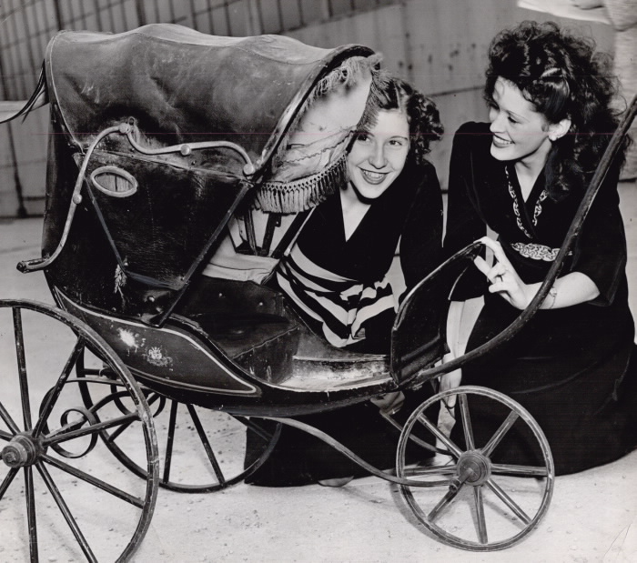 Two women look into an old fashioned stroller