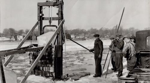 Men with poles use deviceto break up ice on froze river