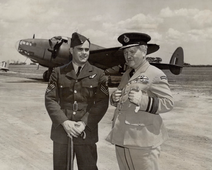 Billy Bishop standing on airfield beside man holding cane