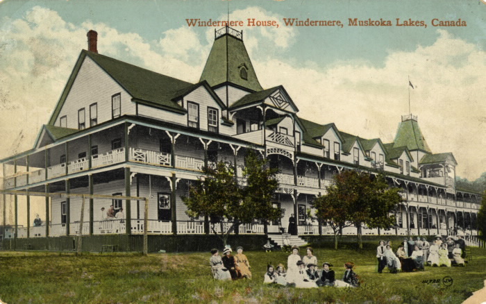 Postcard of country hotel with guests sitting on lawn.