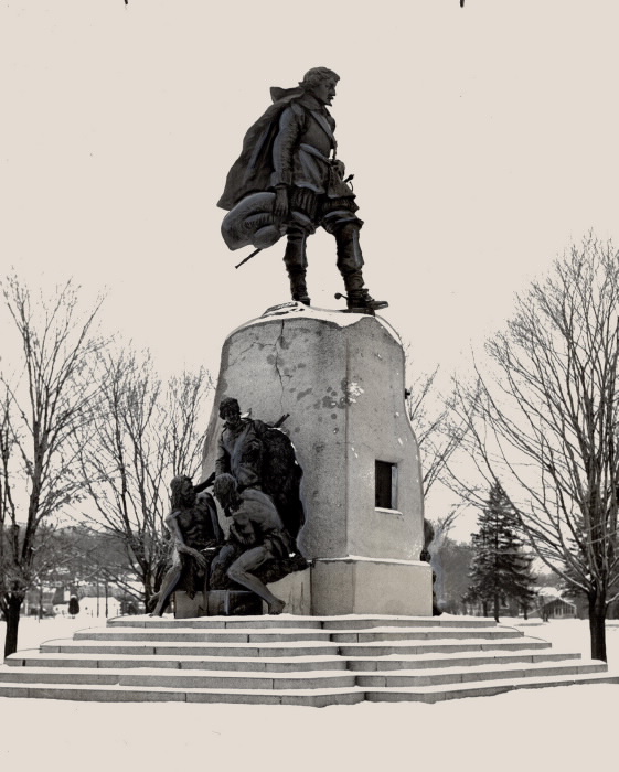 Monument of man in cape towering over other figures below