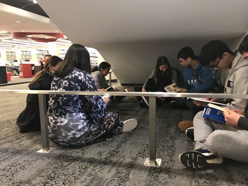 A group of teens sit under a stairwell A group of teens sit under a stairwell