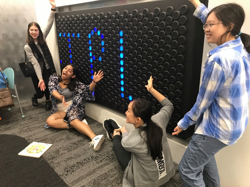 Teens pose in front of a light up wall that says TPL Teens pose in front of a light up wall that says TPL