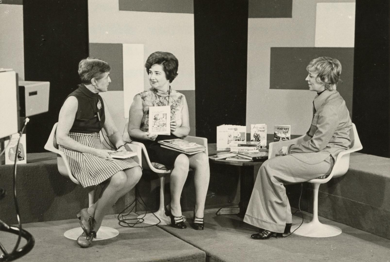 Three women on a retro set of a TV interview show