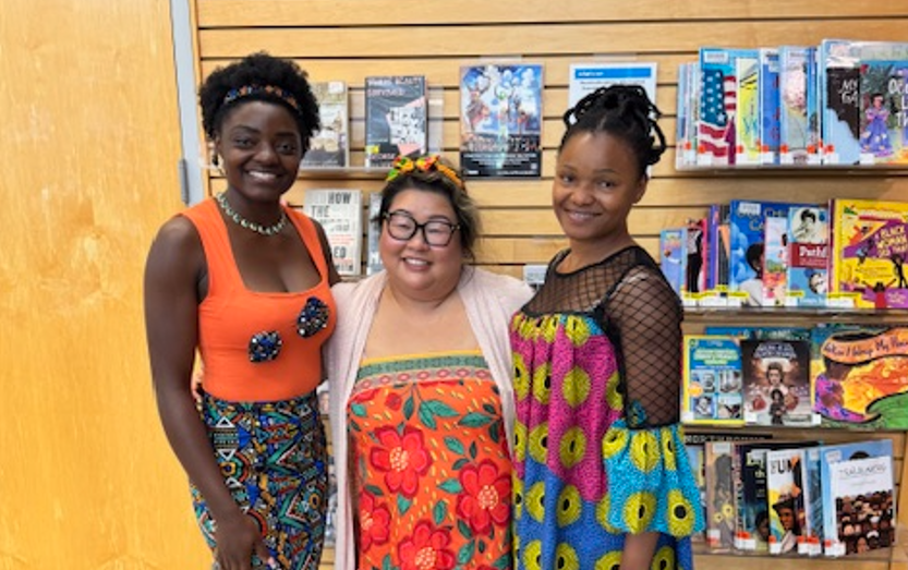 Three people standing together in front of a wall of books.